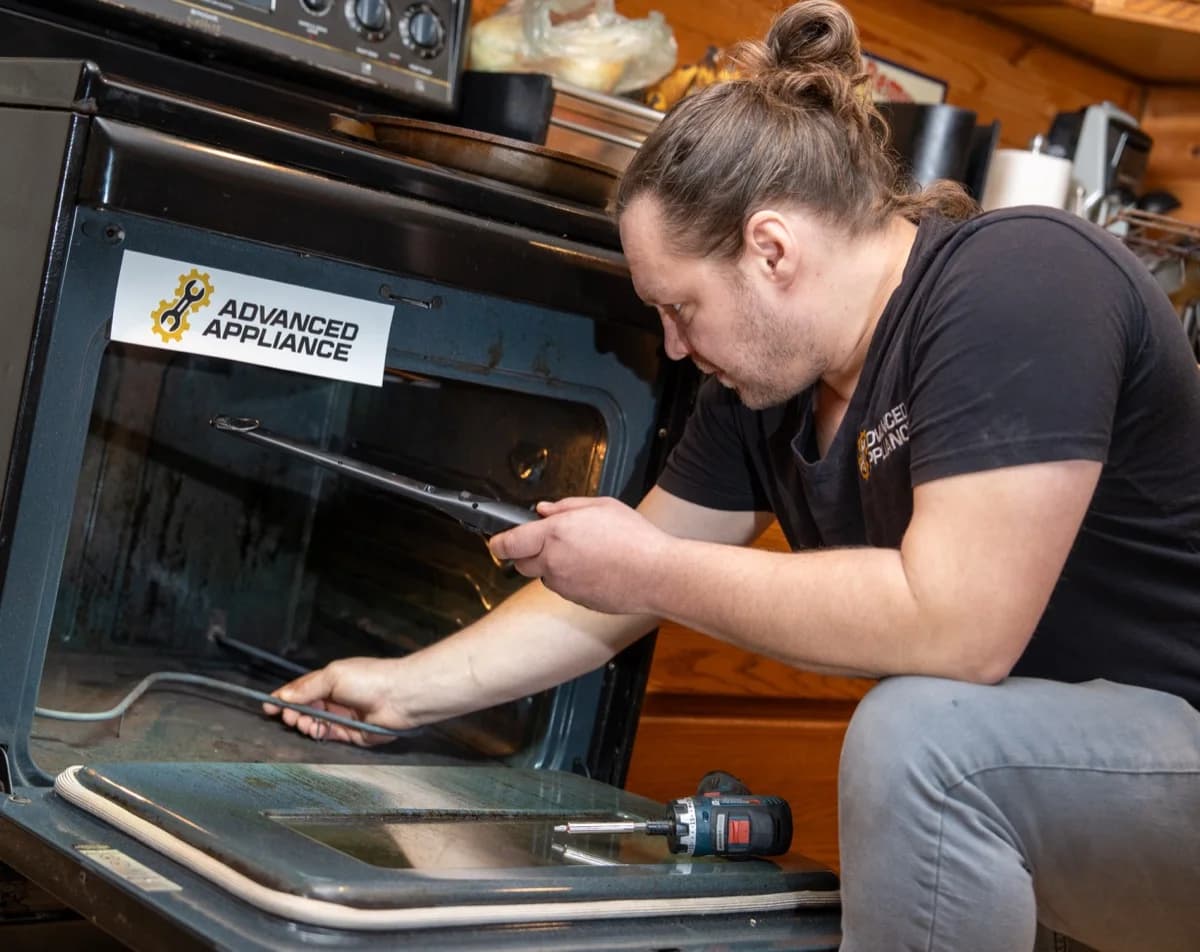 Advanced Appliance technician performing oven repair in a customer's kitchen